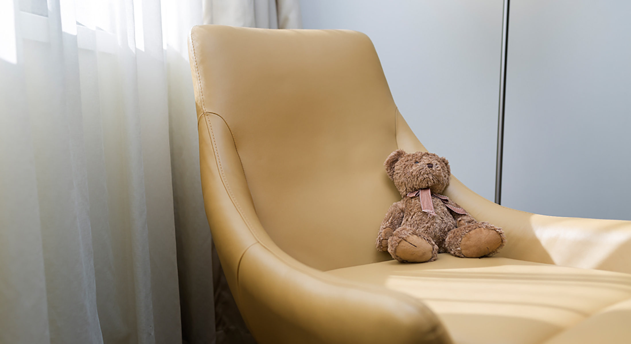 Kids teddy bear rested on in-room arm chair
